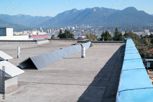 Roof metal flashing or coping installation. Roof repair with new waterproof membrane and sheet metal corners. Flat roof with modified bitumen roofing system with city and mountains. Selective focus.