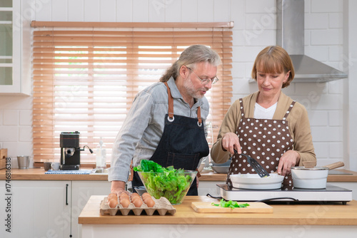 Couple senior elder happy living in home kitchen. Grandmother cooking with grandfather with happiness and smile enjoy retirement life together. Older people relationship and activity.