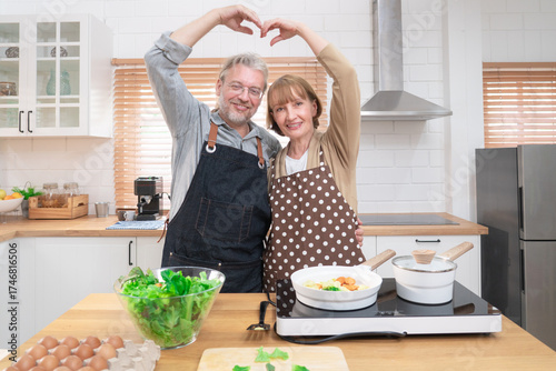 Couple senior elder happy living in home kitchen. Grandmother cooking with grandfather with happiness and smile enjoy retirement life together. Older people relationship and activity.