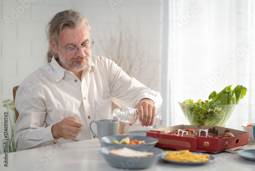 Senior elderly older grandfather stay at home with painful face sitting alone on eating table in house. Depressed elderly retired man upset feeling unhappy. Lonely and missing his family at home	