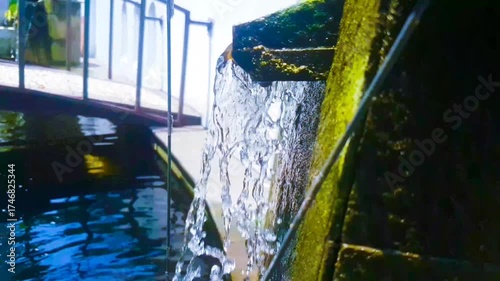 Water cascading from a mosscovered spout into a pool