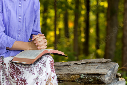 a young lady praying and reading the bible