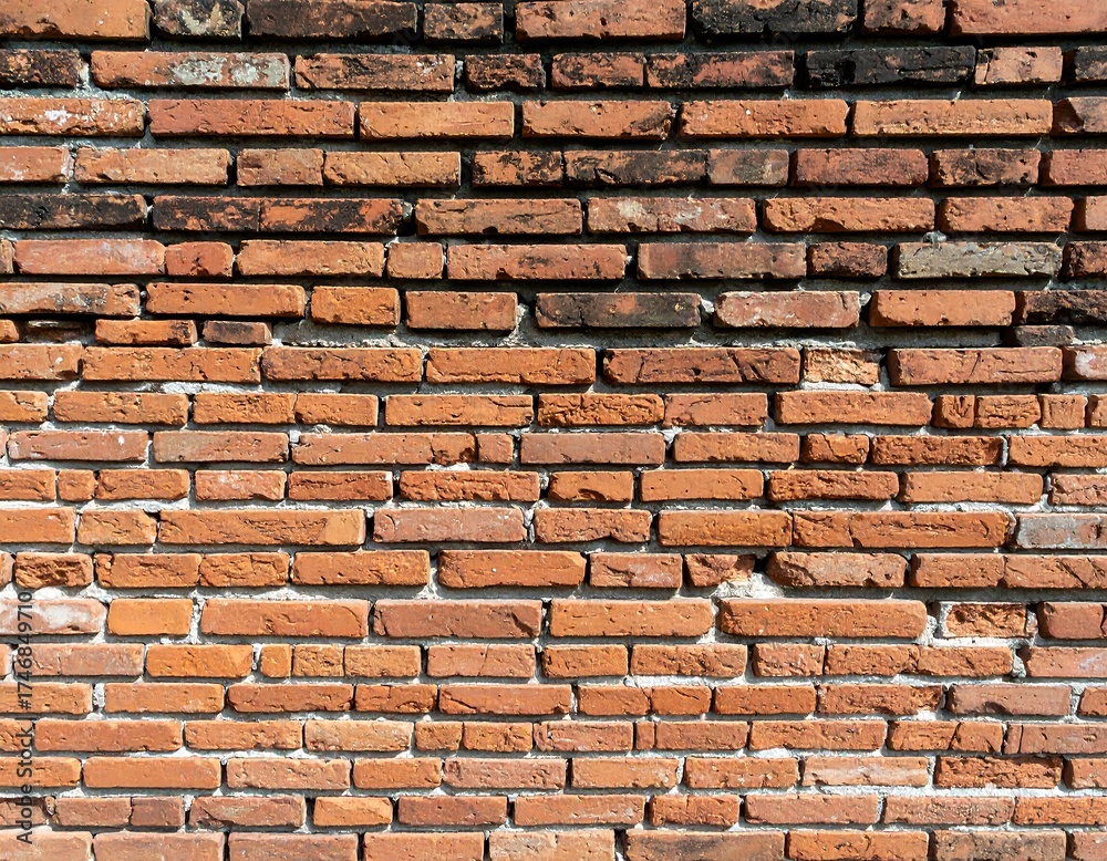 Fototapeta premium A close-up view reveals a textured, weathered brick wall. The arrangement of the rectangular bricks exhibits variations in tone and age