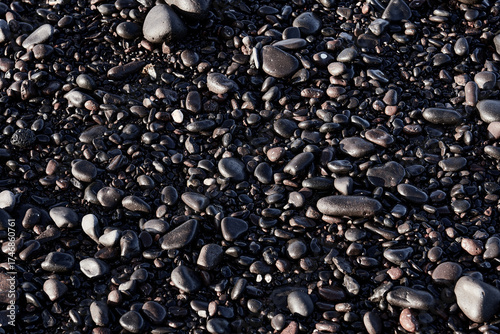 Close-up of wet black volcanic pebbles on the beach - natural texture background