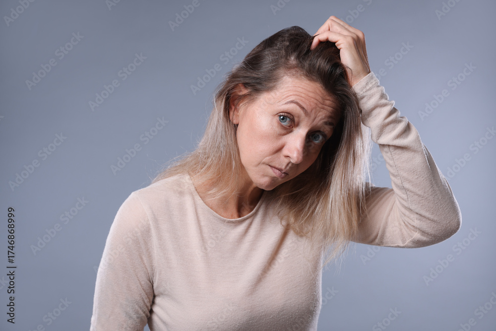 Fototapeta premium Worried woman with hair loss problem on grey background