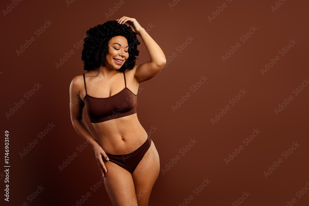 Fototapeta premium Charming young woman posing in brown underwear against a matching background portraying beauty and empowerment