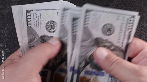 Counting crisp hundred dollar bills in a cozy setting as daylight streams through the window during a quiet afternoon
