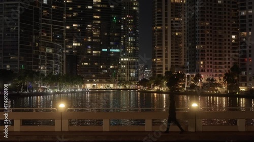 Cinematic footage of a young walking at night in Miami, Florida. Tourist exploring the Brickell area with city lights, skyscrapers, and modern skyline in view