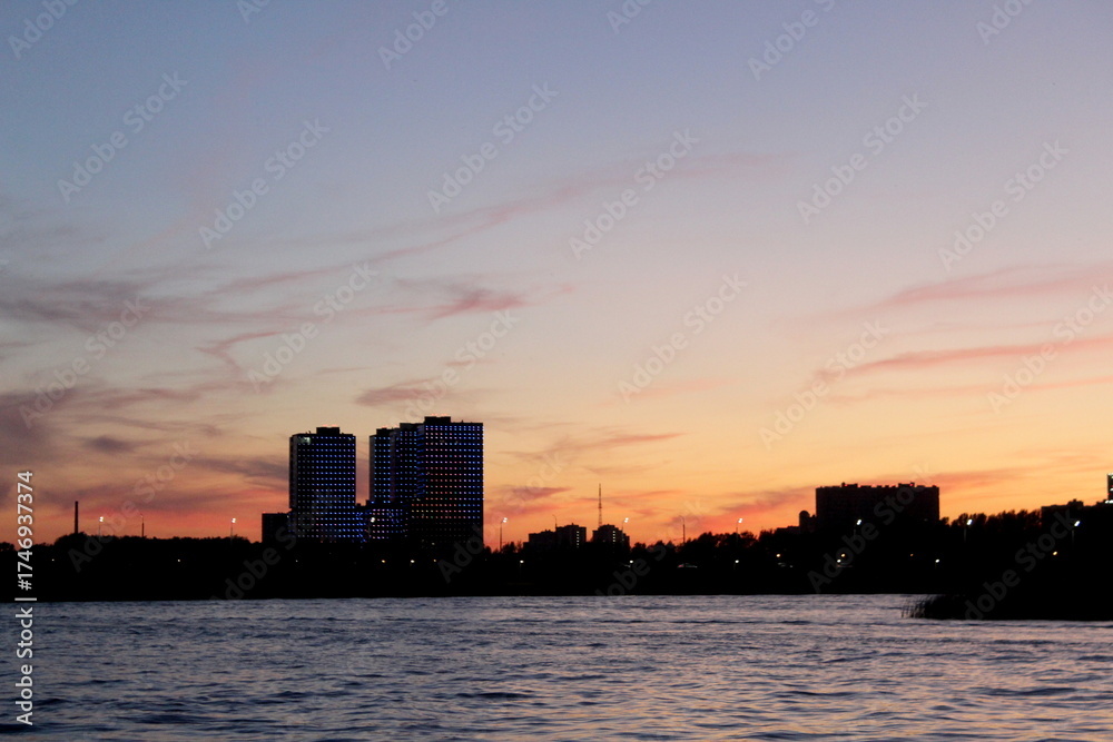 Fototapeta premium Evening city on the river bank in summer.