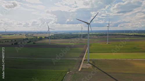 Aerial view of view of large fields with electric windmills in the afternoon sun