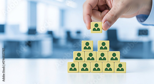 Hand placing a block on a pyramid of blocks representing organizational structure and hierarchy in a business setting