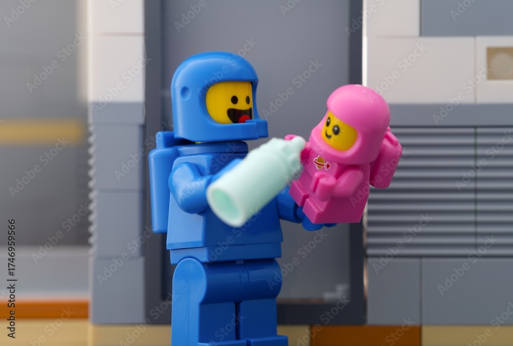 Obraz premium Tambov, Russian Federation - June 07, 2025 Lego astronaut minifigure feeding a baby cosmonaut minifigure using bottle.