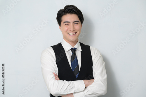 白背景で腕を組む日本人男性