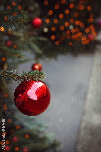 Viele rote, orange Christbaumkugeln, Weihnachtsschmuck hängen an Tannenzweig auf Weihnachtsmarkt, Christkindlmarkt und leuchten, schimmern als verschwommener Hintergrund, Textfreiraum im kalten Winter