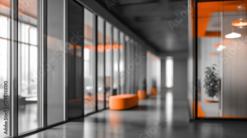 Blurred background of modern office interior in gray tones with panoramic windows and orange accents.