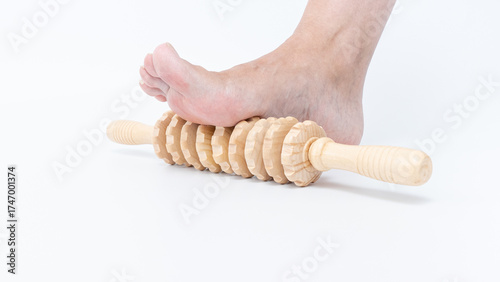 Foot resting on wooden massage roller, showcasing relaxation and wellness, ideal for stress relief and foot care routines in a serene environment