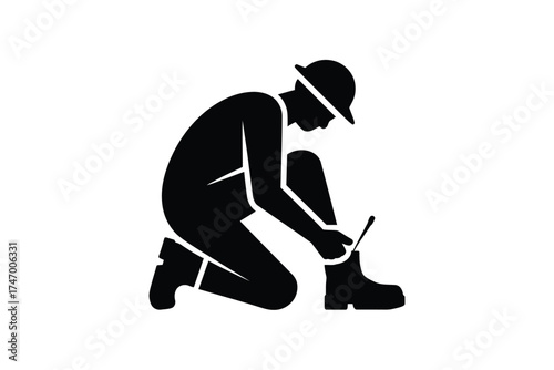 Silhouette of a construction worker in hard hat tying work boots on a white background