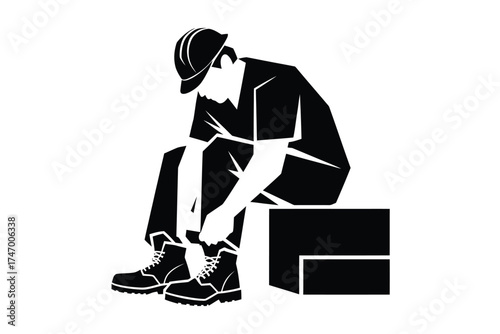 Tired construction worker in hard hat sits on a block tying his work boots