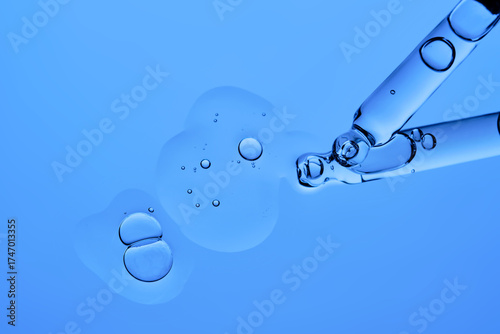 The texture of the serum and two droppers on a blue background.