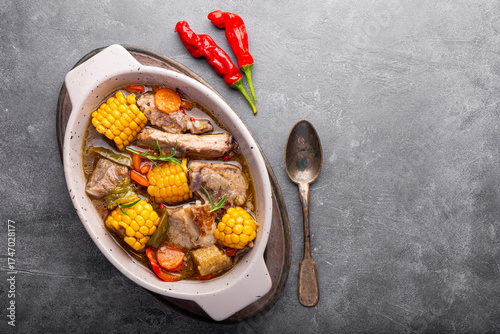 Chilean cuisine of Latin America. Traditional Chilean cazuela de cerdo. Pork soup with potatoes and corn, stew with corn and carrots on grey background top view copy space for text