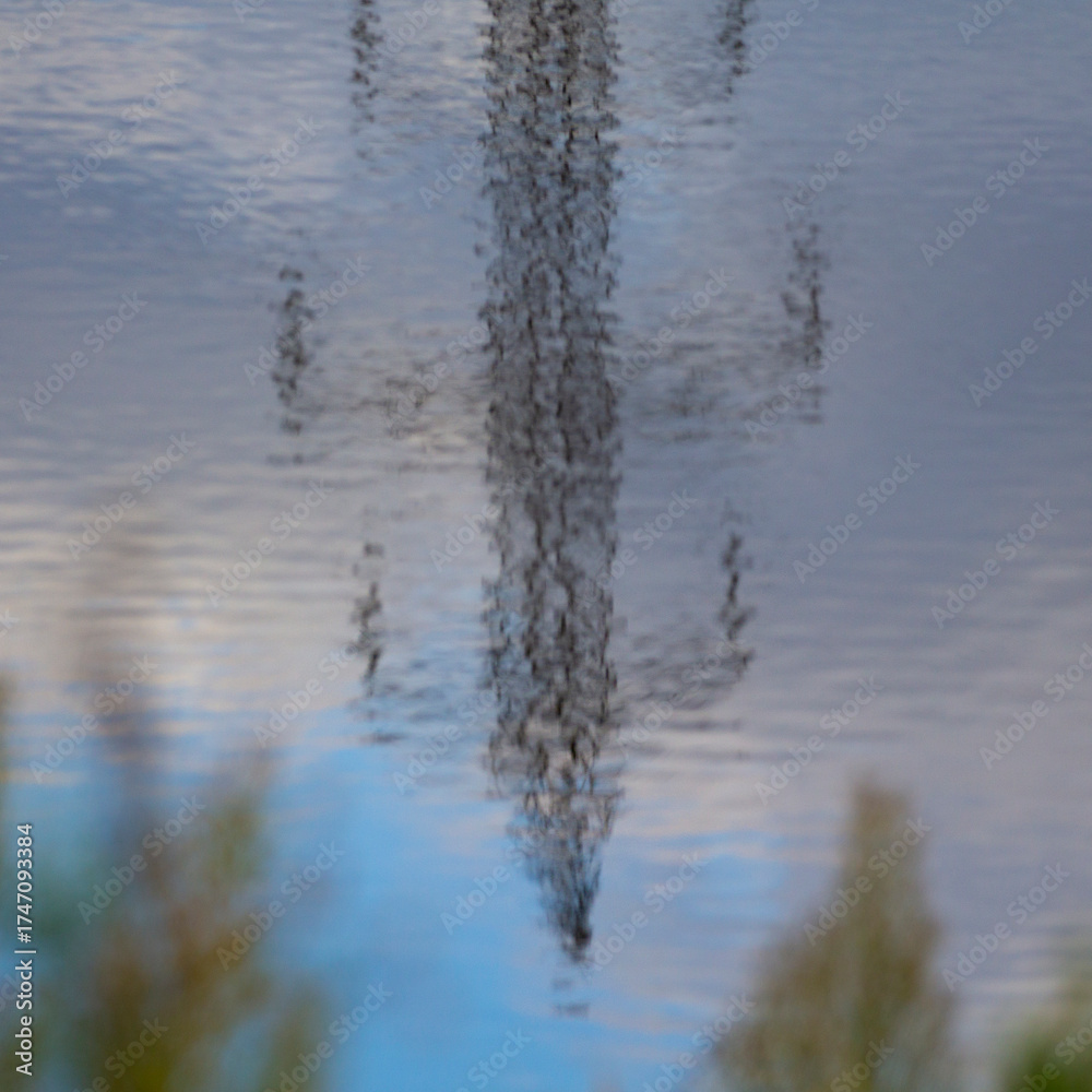 Fototapeta premium A mirror image of a power transmission tower reflected on the surface of the water.