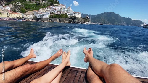 Breathtaking view on mountain hills with old built colourful houses from the sailing motorboat, unforgettable summer vacation of friends sitting on deck boat, relaxing and enjoying Amalfi coast line