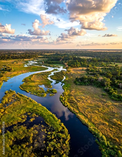 Wallpaper Mural Aerial view of a winding river flowing through a marsh and grassland landscape under a partly cloudy sky at sunset Torontodigital.ca