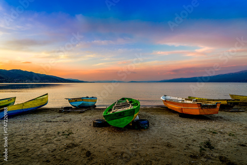 Fotografía Colorful fishing boats resting on the sandy shore of Lake Ohrid at sunset, with