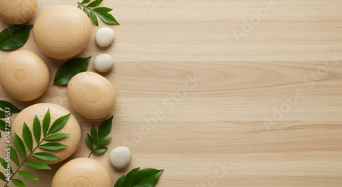 Panel kuchenny z motywem An elegant flat lay composition featuring an assortment of smooth wooden and stone pebbles alongside lush green leaves, all arranged on a light wooden background. Ideal for themes of nature, wellness,