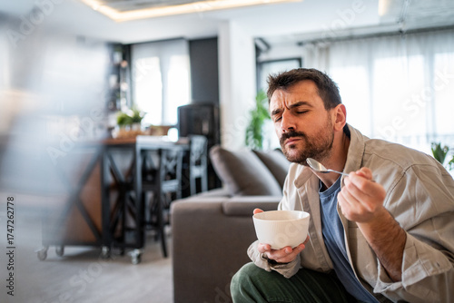 Foto Man feeling distaste after tasting food from bowl