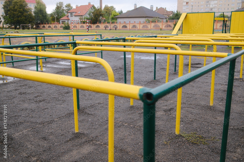 Fototapeta premium Close view shows yellow and green metal monkey bars on the playground in the daytime.