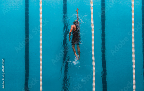 Fotografia Aerial top view of a swimmer in a blue pool performing freestyle stroke between lane dividers