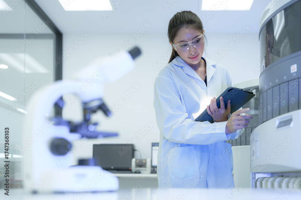 Naklejka premium A laboratory manager reviews the entire workflow, using a tablet to analyze data from microscopy and a high-throughput analyzer, optimizing the process for maximum efficiency.