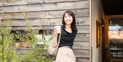 カフェでテイクアウトのコーヒーを持つ女性
