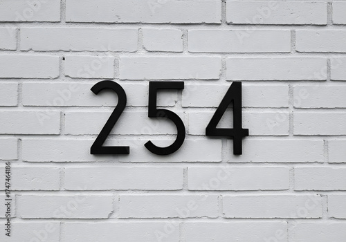 White brick wall with black number sign for identification