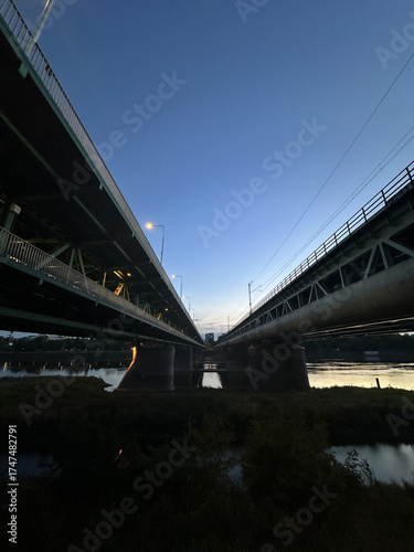 Warsaw, Poland - September 24, 2025: Two parallel bridges spanning a river at dusk, showcasing architectural design and urban infrastructure with reflections on water