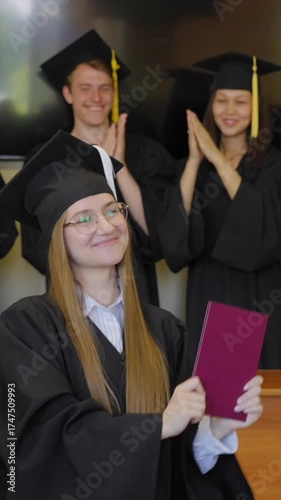 Young Caucasian woman holding diploma while classmates applaud her. 