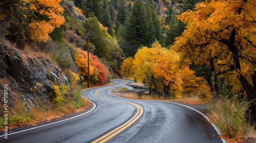 Fototapeta Naklejka Na Ścianę i Meble -  winding road through colorful autumn foliage of a forest, with yellow and orange leaves on the trees. the road curves to one side as it winds along the hillside. late fall season, nature's beauty duri