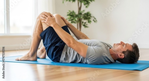 Wallpaper Mural Man lying on yoga mat, pulling knees to chest, stretching Torontodigital.ca