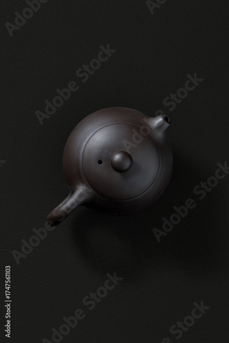 Ceramic teapot with lid and spout, top view on dark background