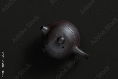 Ceramic teapot with lid and spout, top view on dark background
