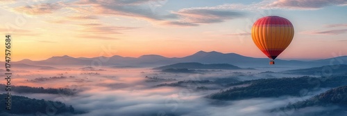 Colorful hot air balloon floating peacefully over misty forested hills during a serene sunrise with soft clouds and distant mountain silhouettes