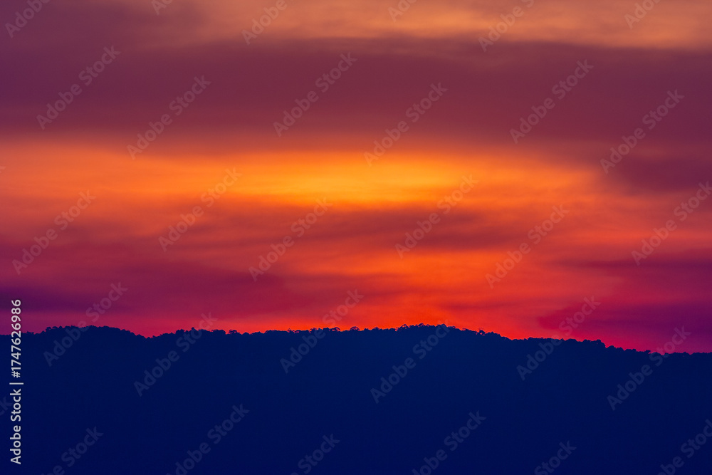 Fototapeta premium Beautiful orange and red clouds at sunrise over the mountain landscape