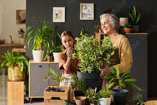 Papier peint Senior Caucasian woman and young Caucasian girl tending houseplants together, bo