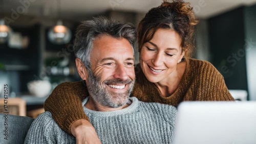 Happy couple shares a warm moment using a laptop in their comfortable home setting