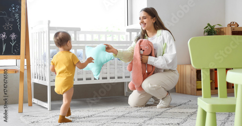 Cute baby girl walking to mother with toys at home