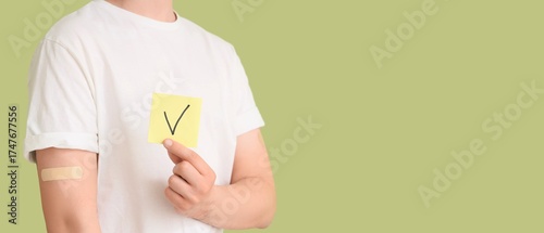Fotografie Young man holding paper with DONE mark on green background with space for text, closeup