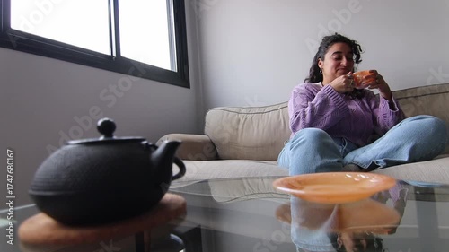 Girl with curly hair drinking coffee on the sofa while talking