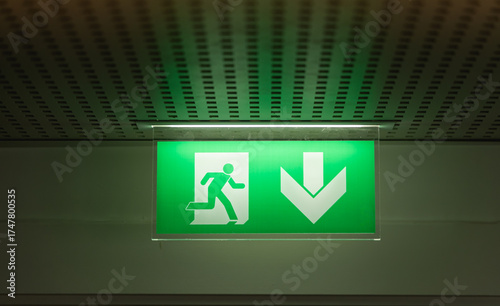 Canvas Print Signalisation de sortie d'urgence au plafond dans un couloir éclairé vert pour indiquer la direction