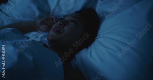 Young Asian Woman Lies Awake at Night, Unable to Sleep. Girl Shifts Uncomfortably, Overwhelmed by Stress and Anxious Thoughts. Concept of Insomnia, Restless Dreams, Mental Tension, Poor Rest.
